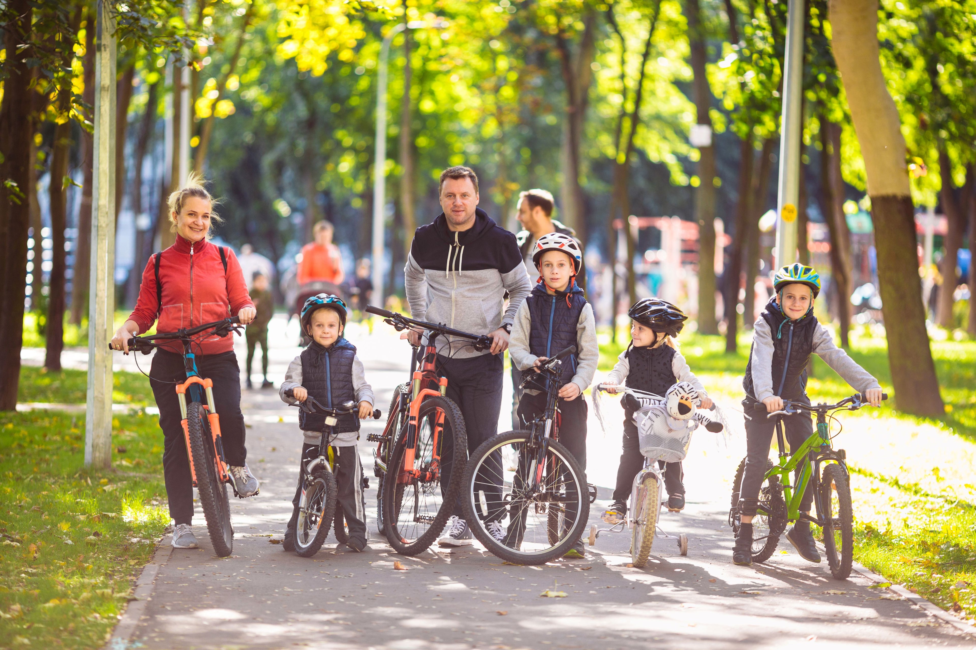 Family with children riding bicycles on a path in a park