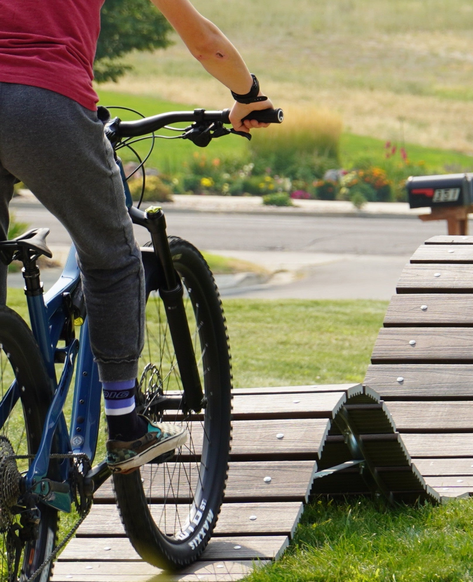 Person on a bicycle near a wooden ramp in an outdoor setting