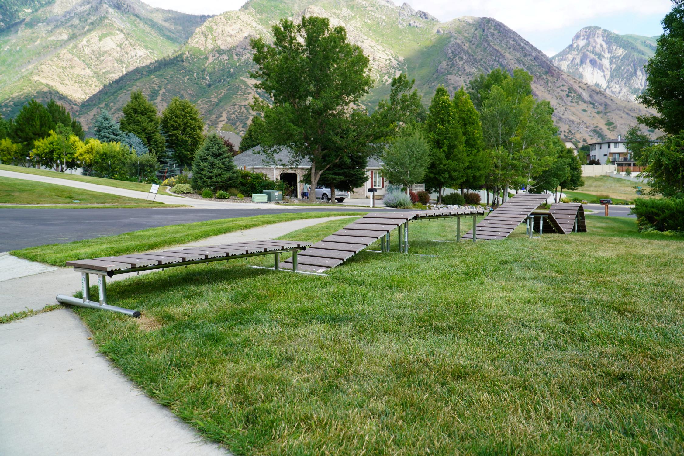 Park with wooden benches and a walking path in front of mountains