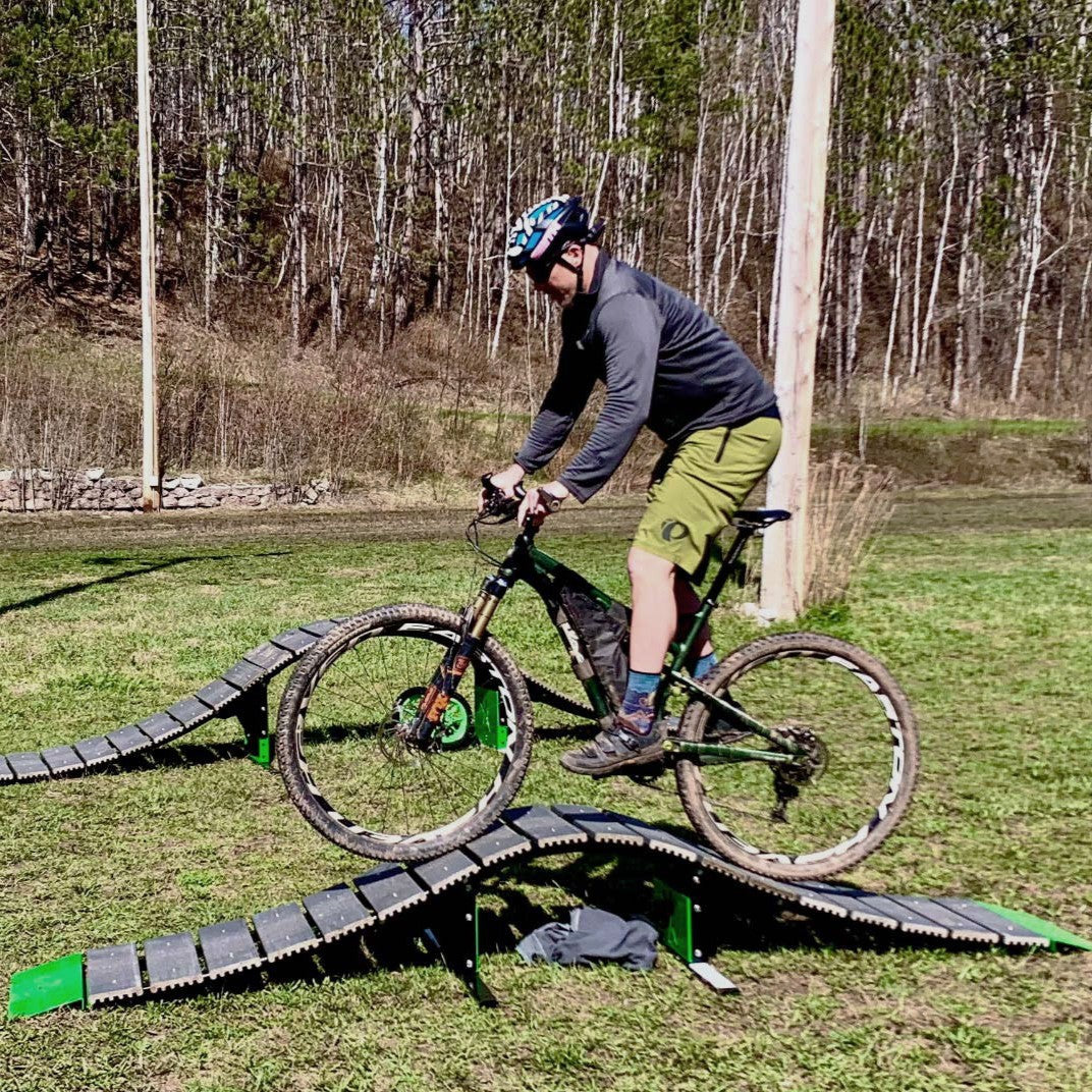 Person riding a bicycle on an outdoor track with trees in the background